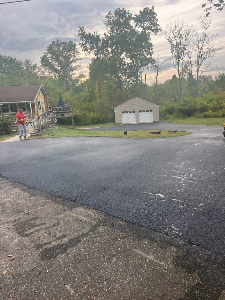 Large new asphalt driveway leading to a detached two-car garage