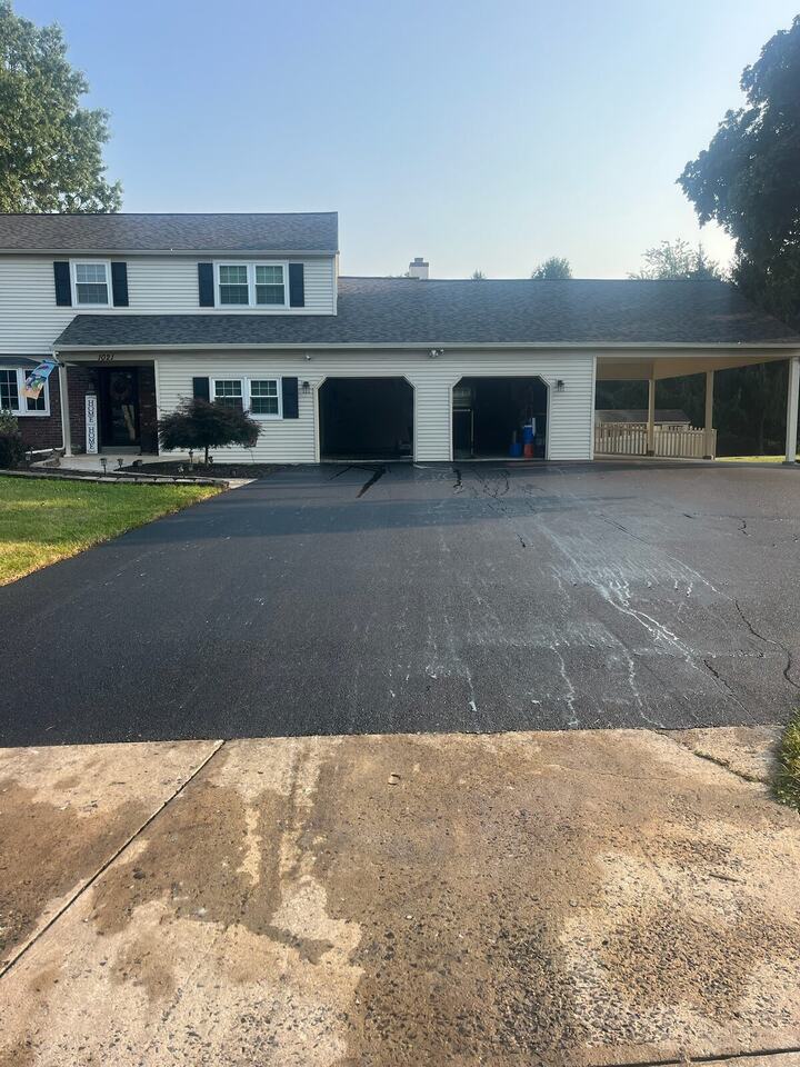 New asphalt driveway in front of a two-story home with an attached garage